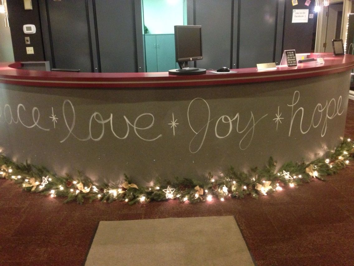 front desk christmas decor a reception counter with writing on it and christmas lights around the